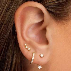 Close-up of elegant 18K gold-plated earring set with zircon inlays on model's ear