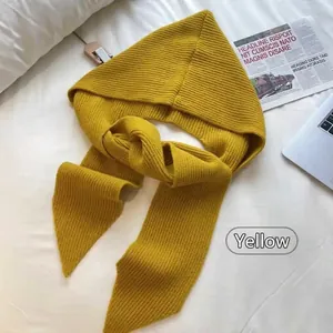 Detail of chunky knit yellow hooded scarf with vertical ribbed texture on white bedding