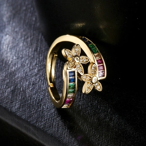 Golden open flower ring with colorful geometric zircons on black leather background
