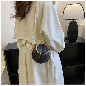 Detail view of a spherical mini evening bag with colorful stripes and gold chain strap