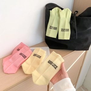 Detail of soft pastel cotton socks with ribbed cuffs and Good Luck lettering