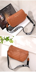 Detail of brown quilted leather bag with stylish embroidered letter wide shoulder strap