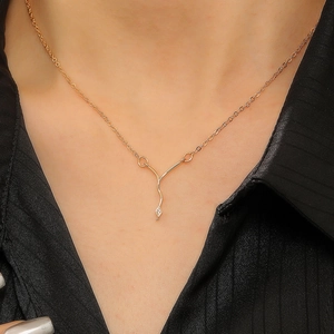 Detail of rose gold snake chain necklace with Y-shaped pendant and small crystal charm