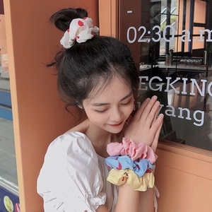 Close-up of floral print scrunchies in pastel colors worn on wrist and in hair bun