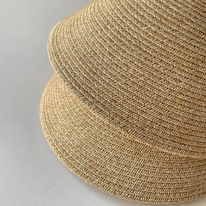 Detailed close-up of fine spiral weaving texture on straw sun visors in natural wood color