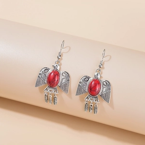 Detail of bohemian silver eagle earrings with red stone inlay and feather tassels