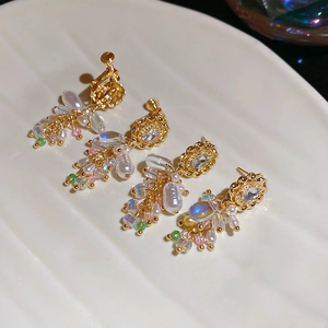 Detailansicht von Vintage-Ohrringen mit Perlen und Kristallen auf weißem Keramikteller