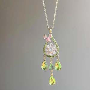 Macro detail of teardrop pendant with zircon butterfly and white floral motif