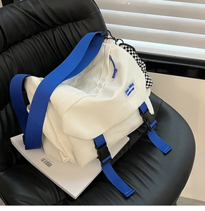 Detail of white nylon messenger bag with blue wide strap and checkerboard pendant
