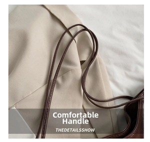 Detail of the slim dual-strap design on a large brown leather tote shoulder bag