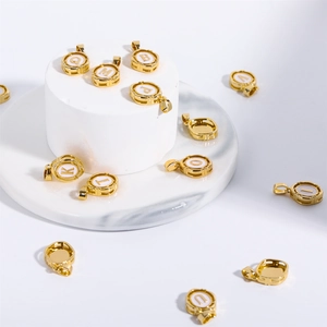 Oval gold pendants with white enamel letters on minimalist display pedestals