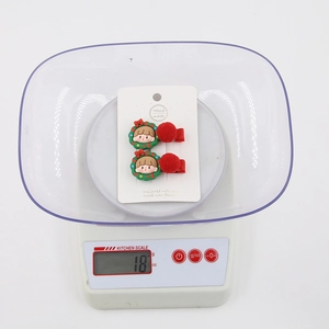 Close-up of red Christmas hair clips set with cartoon girl design on a scale weighing 18g