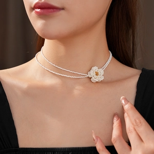 Close-up of double-layer beaded necklace featuring a white pearl-bead flower charm