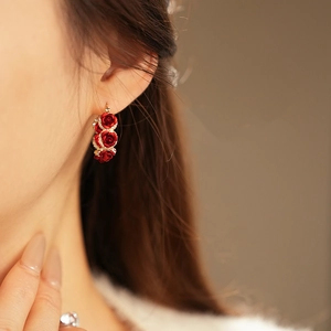 Close-up of gold-plated red rose earrings with rhinestones on a female model