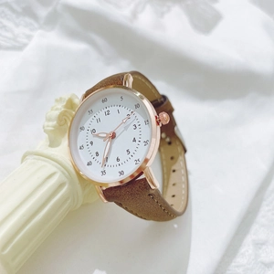 Elegante orologio oro rosa con quadrante bianco e cinturino in pelle marrone su colonna