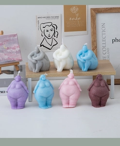Artistic body sculpture scented candles in various colors on an aesthetic desk setup