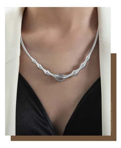Detailed view of a silver spring-textured necklace on model with minimalist business attire