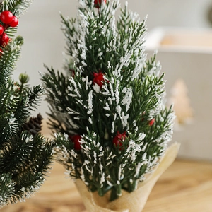 Mini artificial green Christmas tree with red berries and snow on burlap base