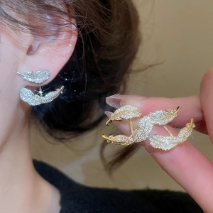 Close-up of gold-plated feather earrings with pavé zircons showing model wear and details