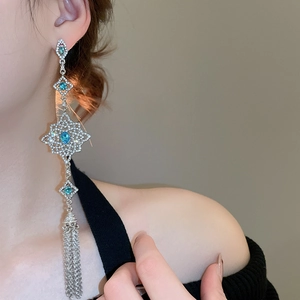 Detail of silver needle earrings with blue crystals and long tassels on model