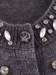 Close-up of knit fabric with rhinestone neckline and marble-textured button detail