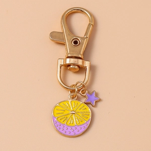Macro shot of creative yellow and purple lemon slice charms with stars on gold keychain
