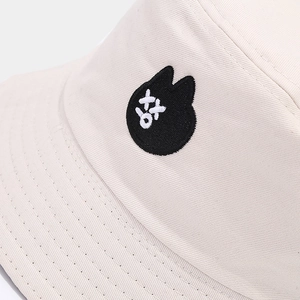 Vue détaillée de la broderie sur un chapeau bob crème avec un écusson de chat