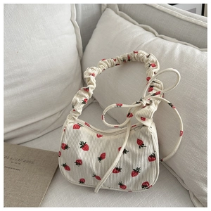 Detail of strawberry print corduroy shoulder bag with ruffled strap and zipper closure