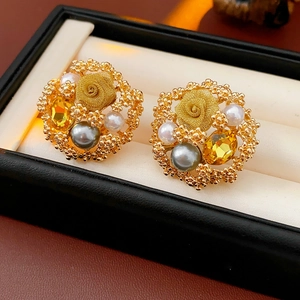 Détail de boucles d'oreilles fleur vintage avec pierres jaunes et perles grises en boîte