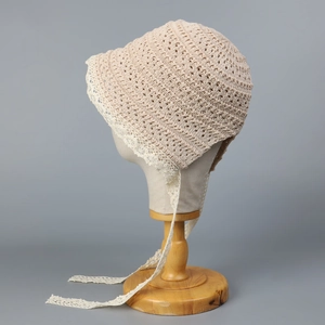 Detail view of beige crochet baby sun hat featuring intricate white lace trim and ties