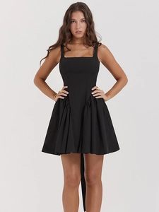 Detail view of black backless mini dress featuring ruffled hem and side pleats