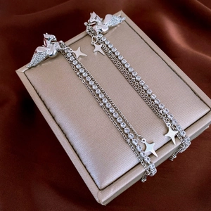Detail view of silver pegasus tassel earrings with star charms and sparkling zircons
