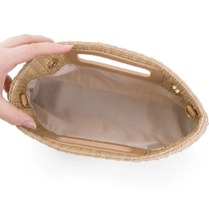 Detailed interior view of straw woven clutch featuring beige fabric lining and gold magnetic closure