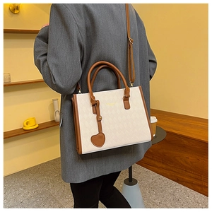 Chic beige quilted tote bag with brown trim shown from behind on model's shoulder