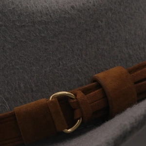 Detailed close-up of grey wool felt fedora with brown suede band and gold ring buckle
