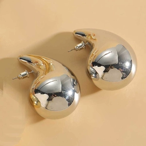 Macro shot of minimalist gold teardrop earrings with a high-polished mirror finish surface