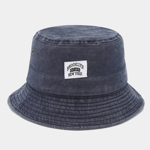 Détail d'un bob en jean délavé gris avec étiquette Brooklyn et œillets d'aération en métal