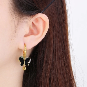 Detail of gold butterfly drop earring with enamel inlay and pavé accents on model