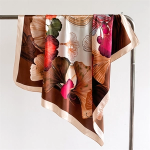 Silk-satin square scarf with ginkgo leaf print in brown and red hanging on a hanger