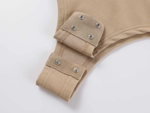 Close-up of three metal snap buttons on the khaki cotton bodysuit bottom closure