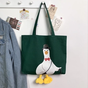 Detail of dark green canvas tote featuring cartoon duck with 3D plush webbed feet