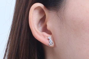 Close-up of a silver cat-shaped stud earring worn on ear with professional focus