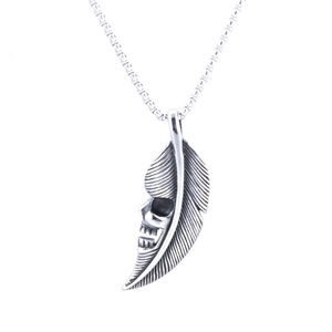 Macro shot of a vintage punk silver skull and feather pendant with turquoise accent