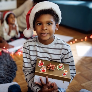 Close-up of holographic Christmas stickers on a gift box held by a happy child