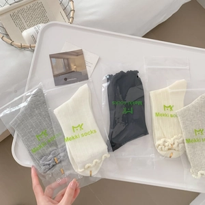 Detail of multi-color ruffle cuff socks in transparent packaging on a white tray