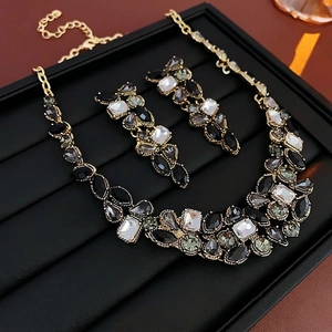Parure de bijoux vintage dorée avec cristaux goutte d'eau noirs sur étui cuir