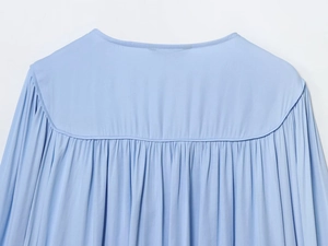 Detailweergave van de fijne plooien en naden op de lichtblauwe chiffon blouse voor dames