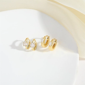 Detailed view of gold hoop earrings with sparkling zircon stones on silk fabric