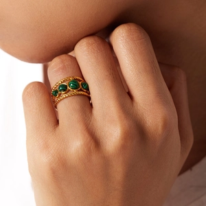Detailed view of layered 18K gold ring with three oval green natural stones on finger