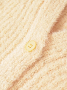 Gros plan détaillé du cardigan en maille crème texturée avec bouton en résine
